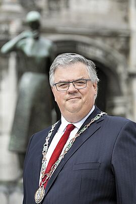 Portretfoto Burgemeester Bruls met Marikenbeeld op de achtergrond